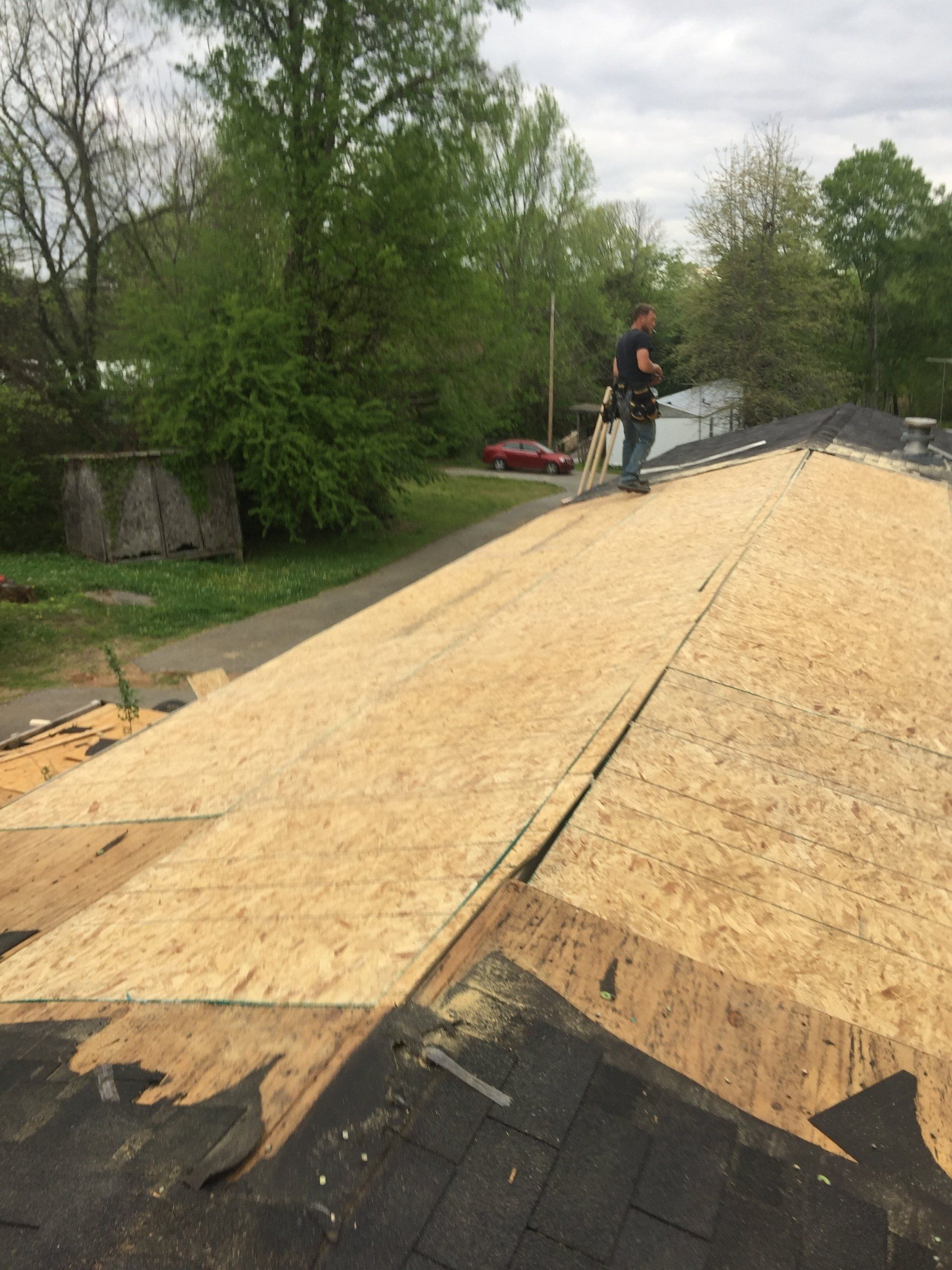 Professional roofer inspecting newly installed wood sheathing before roof replacement