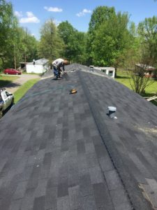 Professional roofer completes installation of asphalt shingles in a roof replacement project